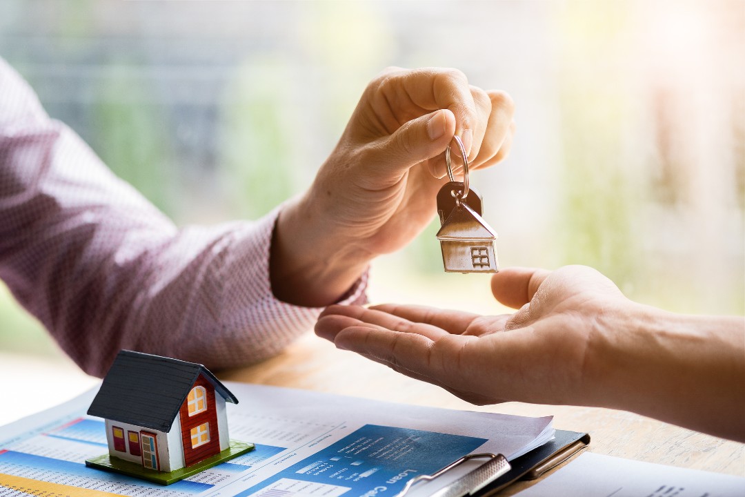 Real estate agent handing over keys to customer after signing rental lease contract of sale purchase agreement