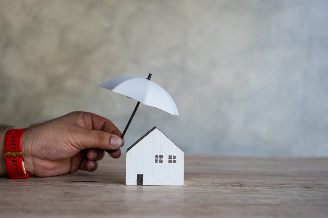 A hand holding white tiny umbrellas to cover white model house