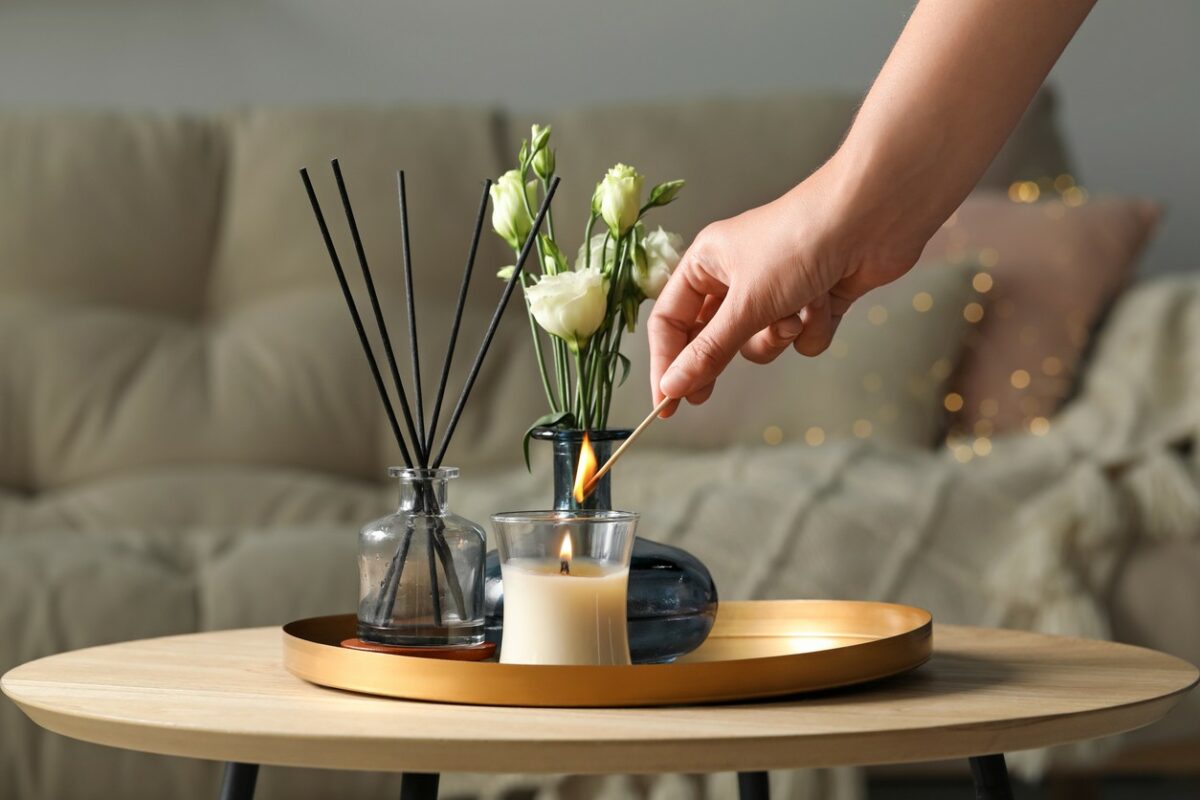 Woman lighting candle at wooden table in living room